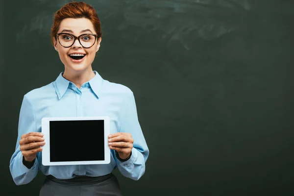 Aufgeregter Lehrer zeigt digitales Tablet mit leerem Bildschirm neben Tafel — Stockfoto