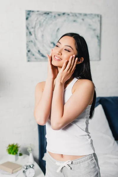 Belle asiatique femme sourire tout toucher visage à la maison — Photo de stock