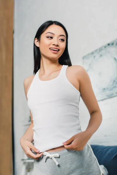 Foco seletivo de bela mulher asiática sorrindo e olhando para o espelho em casa — Fotografia de Stock