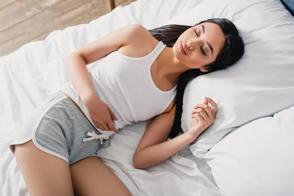 Вид зверху красива азіатська жінка в піжамі спить на ліжку вранці — стокове фото