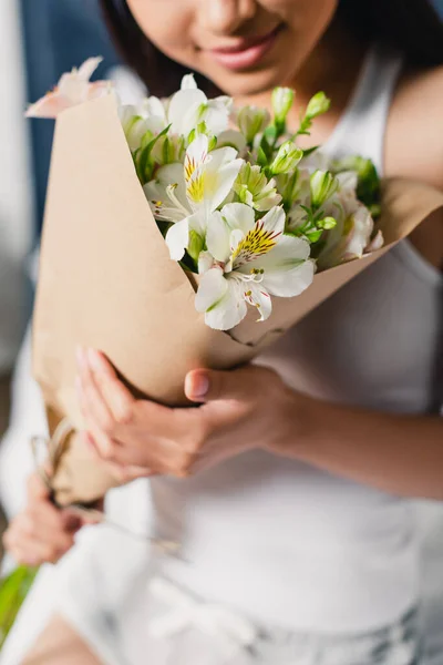 Ausgeschnittene Ansicht einer jungen Frau, die zu Hause einen Strauß Alstroemerien hält — Stockfoto