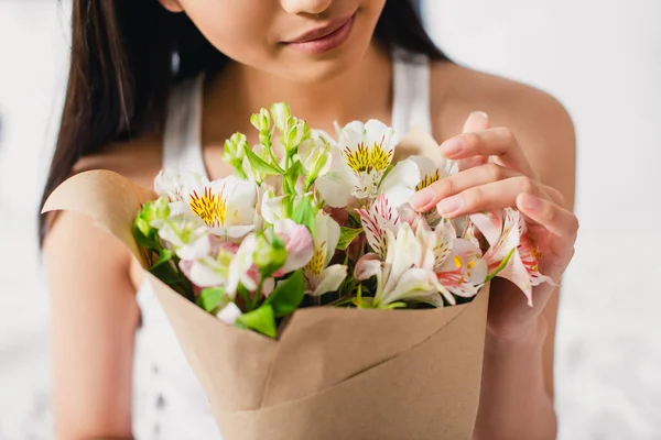 Cropped view of young woman touching flowers in bouquet — Stock Photo