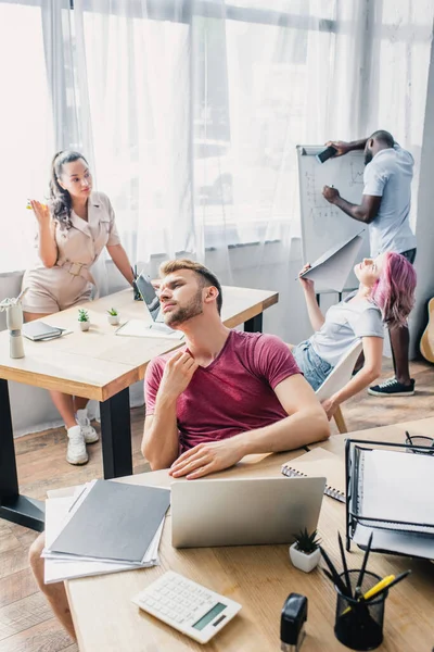 Enfoque selectivo de las personas de negocios multiétnicos agotados que sufren de calor en la oficina - foto de stock