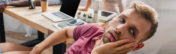 Панорамний знімок втомленого бізнесмена, який страждає від спеки з колегами на задньому плані — стокове фото