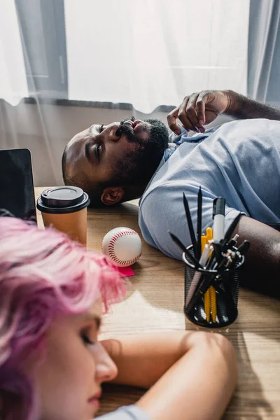 Selective focus of african amercian businessman feeling hot near colleague at table in office — Stock Photo