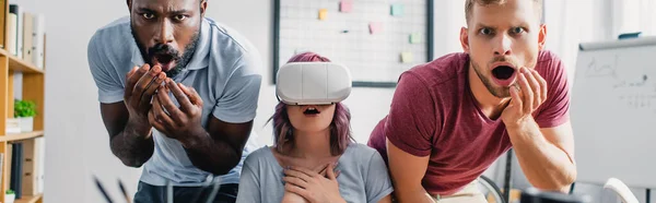 Foto panorámica de gente de negocios multicultural impactada con auriculares vr en la oficina - foto de stock