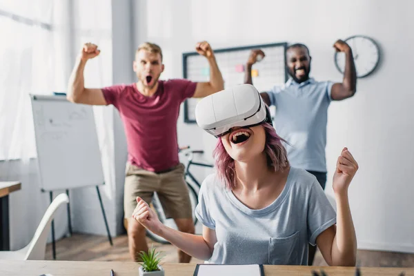 Foco seletivo da mulher de negócios no fone de ouvido vr mostrando sim gesto com colegas multiculturais no fundo — Fotografia de Stock