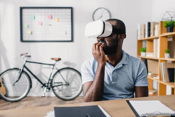 Selective focus of scared african american businessman using vr headset in office — Stock Photo