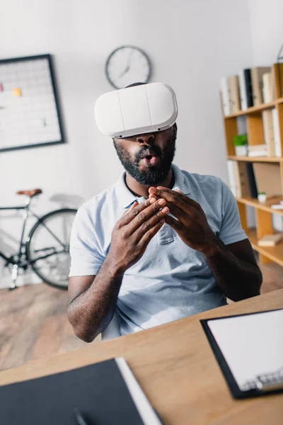 Selective focus of excited african american businessman using virtual reality headset in office — Stock Photo