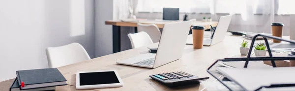 Панорамний знімок ноутбуків, калькулятора і цифрових пристроїв на офісному столі — стокове фото