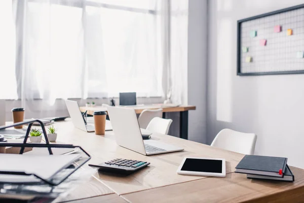 Enfoque selectivo de la tableta digital, computadoras portátiles y papelería en la mesa de oficina - foto de stock