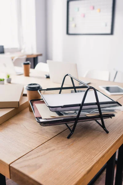 Selective focus of document tray near coffee to go on table in office — Stock Photo