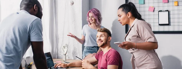 Panoramic crop of multiethnic business people using digital devices while working in office — Stock Photo