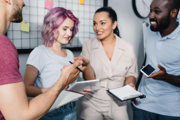 Foco seletivo do empresário apontando com a mão enquanto trabalhava com colegas multiétnicos no escritório — Stock Photo