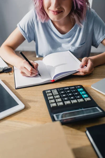 Vue recadrée de jeune femme d'affaires écrivant sur ordinateur portable près de la calculatrice et tablette numérique sur la table — Photo de stock