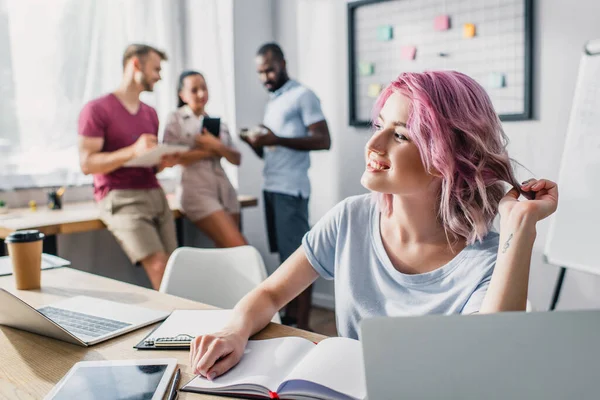 Enfoque selectivo de la mujer de negocios sentada cerca de portátil y dispositivos digitales en la mesa en la oficina - foto de stock