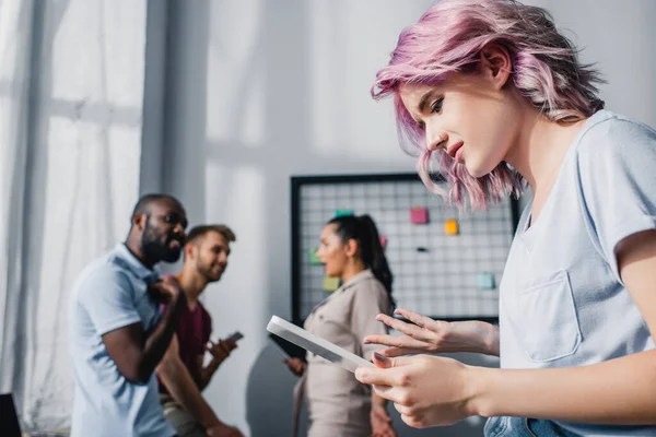 Focus selettivo della giovane imprenditrice che utilizza tablet digitale con colleghi multietnici in carica — Foto stock