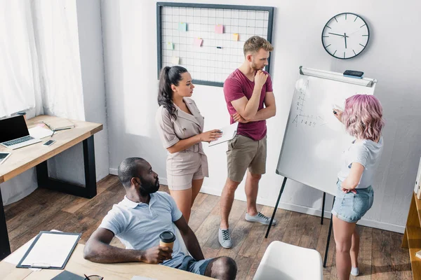 Hohe Blickwinkel auf multiethnische Geschäftsleute, die im Büro mit Whiteboard arbeiten — Stockfoto