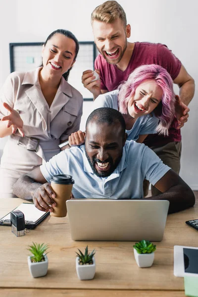 Foco seletivo de pessoas de negócios multiétnicas usando laptop juntos no escritório — Fotografia de Stock