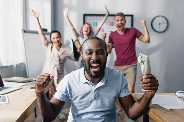 Selective focus of african american businessman showing yeah gesture with colleagues at background — Stock Photo