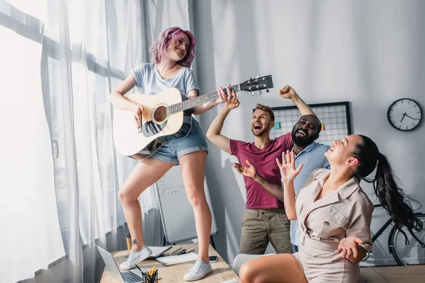 Multiethnische Geschäftsleute spielen Akustikgitarre und tanzen im Büro — Stockfoto