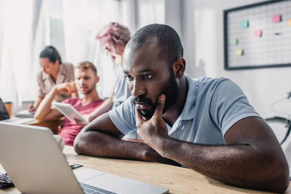 Foco seletivo do empresário afro-americano focado olhando para o laptop na mesa no escritório — Fotografia de Stock