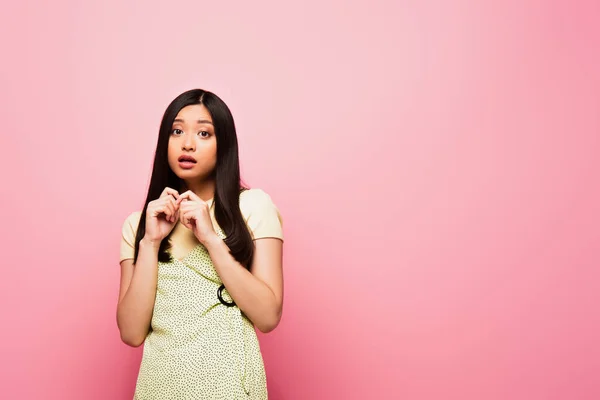 Scared asian girl looking at camera on pink — Stock Photo