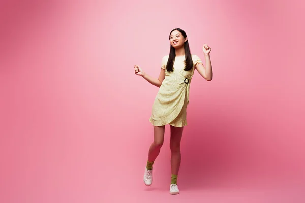 Alegre asiático menina no vestido dançando no rosa — Fotografia de Stock