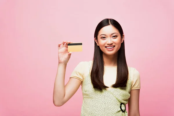 Sourire jeune asiatique femme tenant carte de crédit isolé sur rose — Photo de stock