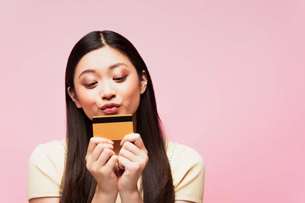 Attraente e giovane asiatico donna baci carta di credito isolato su rosa — Foto stock