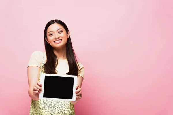 Cheerful asian woman holding digital tablet with blank screen on pink — Stock Photo