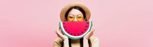 Website header of asian girl in sunglasses and straw hat covering face with paper watermelon isolated on pink — Stock Photo