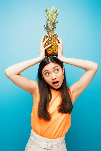 Émotionnel asiatique fille tenue mûr ananas sur bleu — Photo de stock