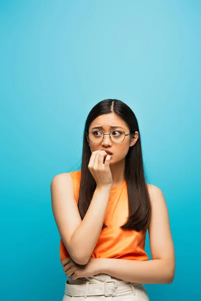 Jeune et inquiet asiatique femme toucher la bouche sur bleu — Photo de stock