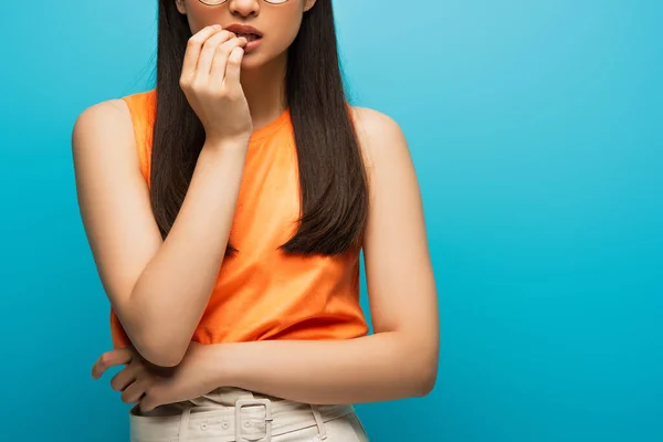 Abgeschnittene Ansicht einer besorgten Frau, die den Mund isoliert auf blauem Grund berührt — Stockfoto