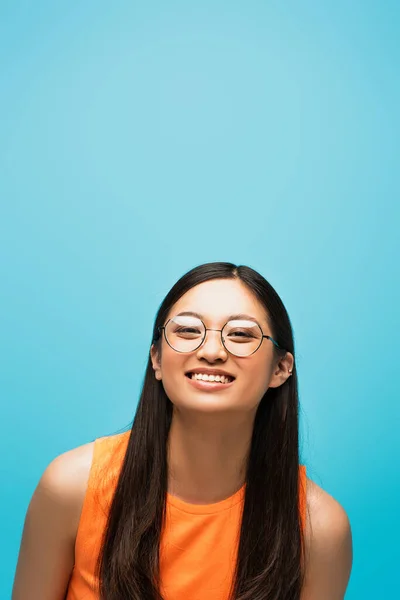 Fröhliche asiatische Mädchen mit Brille lächeln isoliert auf blau — Stockfoto