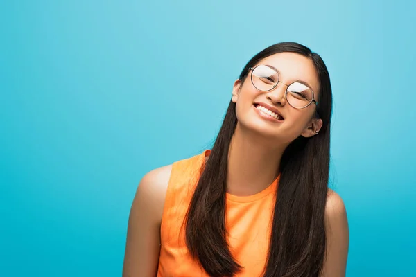 Positivo asiático menina no óculos sorrindo isolado no azul — Fotografia de Stock