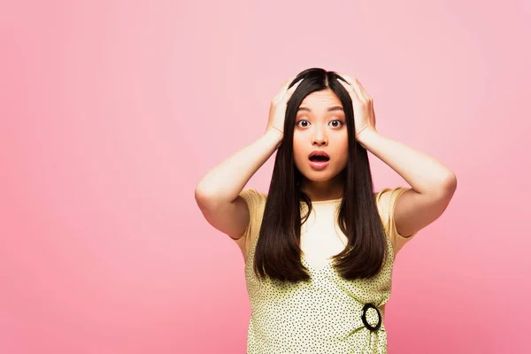 Shocked asian girl touching head and looking at camera isolated on pink — Stock Photo
