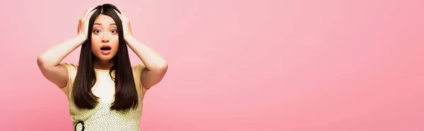 Panoramic concept of shocked asian girl touching head and looking at camera isolated on pink — Stock Photo