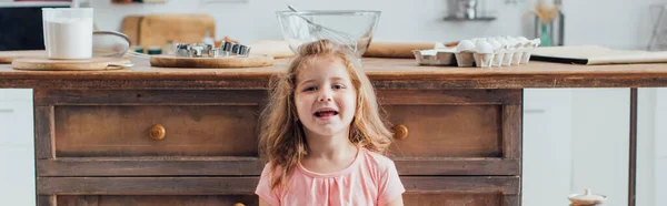 Website-Header des blonden Mädchens blickt in die Kamera in der Nähe des Küchentisches mit Zutaten und Kochutensilien — Stockfoto