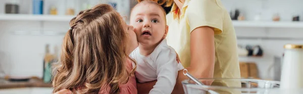 Partial view of mother holding little son while daughter kissing him, panoramic shot — Stock Photo