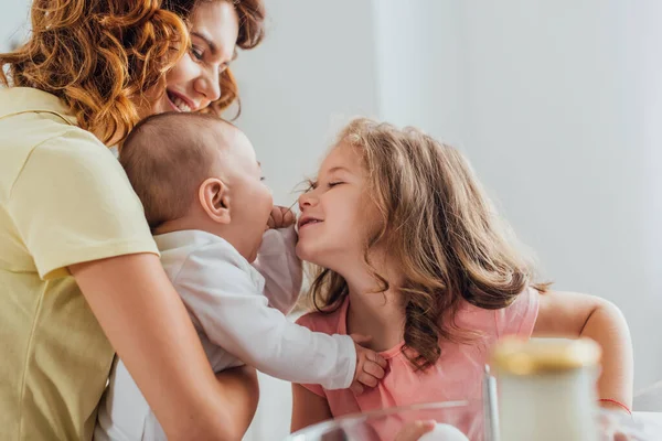 Selektiver Fokus einer jungen Mutter, die ihren kleinen Sohn hält, während sich die Tochter an ihn lehnt — Stockfoto