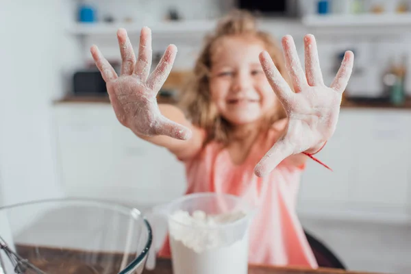 Selective focus of girl showing hands in flour near measuring jug and glass bowl, panoramic shot — Stock Photo