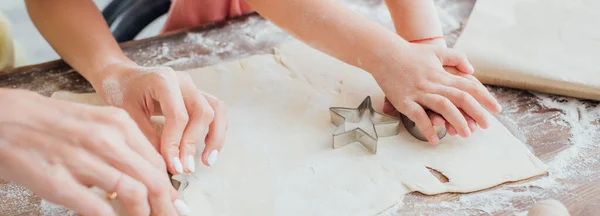 Vue partielle de la femme et de l'enfant découpant les biscuits de la pâte roulée près du moule en forme d'étoile, concept panoramique — Photo de stock