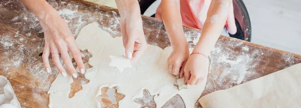 Vue recadrée de maman et d'enfant découpant les biscuits multi-formes de la pâte roulée — Photo de stock