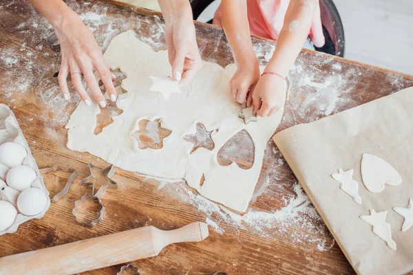 Vista dall'alto della mamma e del bambino che ritagliano biscotti multi-forma dalla pasta arrotolata — Foto stock
