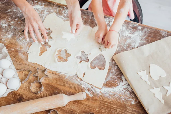 Vista superior da mãe e da criança cortando biscoitos em forma de multi da massa rolada — Fotografia de Stock