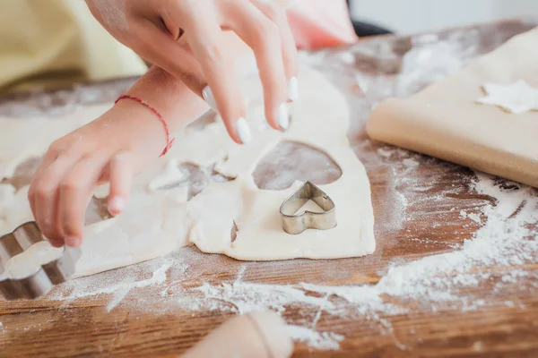 Cropped view of mother and daughter near rolled dough and cookie cutters on table scattered with flour — Stock Photo