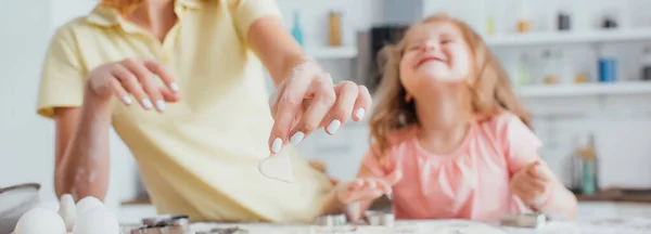 Vista cortada da mãe segurando biscoito cru em forma de coração perto da filha na mesa da cozinha, foco seletivo — Fotografia de Stock