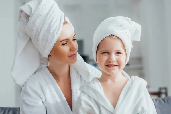 Jovem mãe e criança em roupões de banho brancos e toalhas na cabeça em casa — Fotografia de Stock